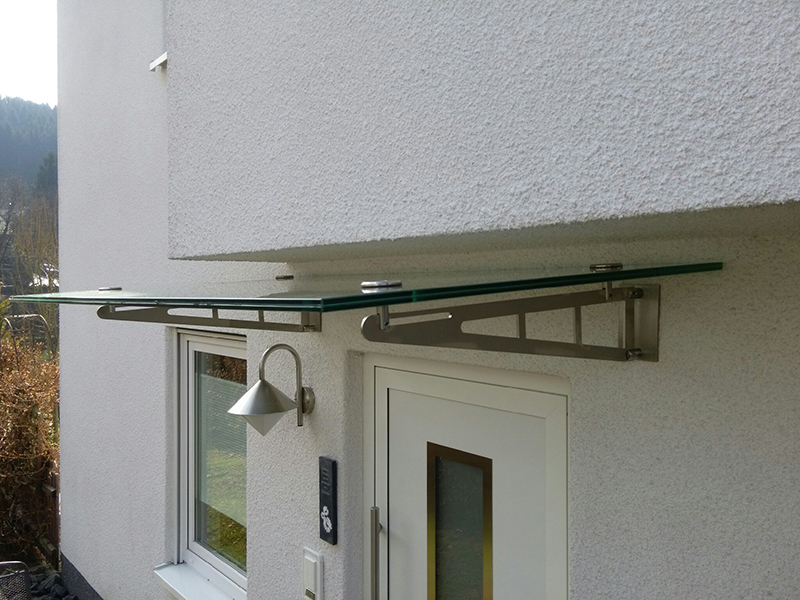 Vordach aus Edelstahl mit Glasfüllung über einer Haustür